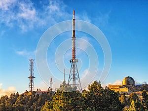 Telecommunication towers with TV antennas and satellite dish in sunset