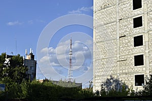 A telecommunications antenna in the city and a Ferris wheel with a big house and a blue sky