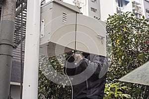 A telecommunications maintenance worker is checking equipment