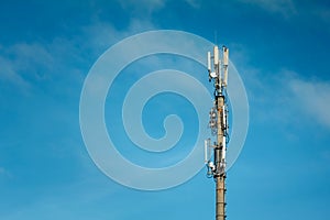 Telecommunications mast set against blue sky and big white cloud
