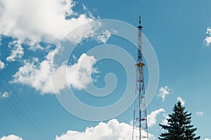 Telecommunications mast set against blue sky and big white cloud