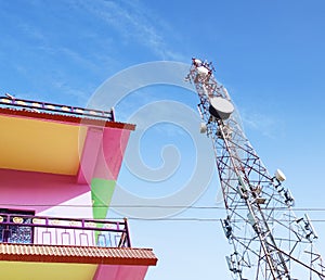 Telecommunications satellite mobile tower with beautiful house in blue sky background, tower in resi