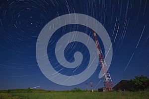 Telecommunications tower in a field and star trail