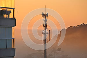 Telecommunications tower in the middle of houses in the morning fog.
