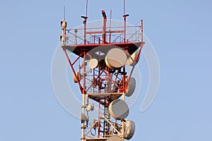 Telecommunications tower and satellite dish telecom network on blue sky with bright sun light