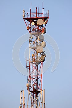 Telecommunications tower and satellite dish telecom network on blue sky with bright sun light