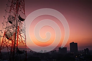 Telecommunications tower and satellite dish telecom network with silhouette of countryside area in sunrise