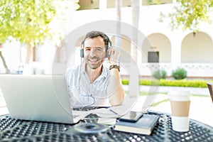 Telecommuter Communicating On Headphones Connected To Laptop photo