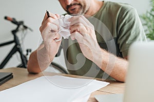 Telecommuter with creative block in home office crumpling sheet of paper photo