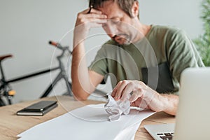 Telecommuter with creative block in home office crumpling sheet of paper photo