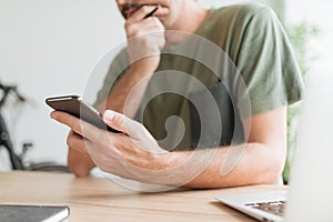 Telecommuter reading text message on mobile smart phone in home office photo