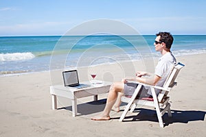Telecommuting, businessman with laptop on the beach photo