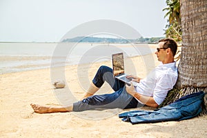 Telecommuting, businessman relaxing on the beach with laptop and palm, freelancer workplace, dream job.