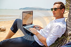 Telecommuting, businessman relaxing on the beach with laptop and palm, freelancer workplace, dream job.