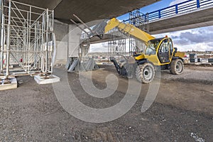 Telehandler on a construction site, preparing to raise construction parts photo