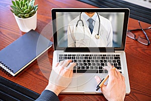 Telemedicine concept. Doctor GP on a computer screen, office desk background