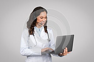 Telemedicine concept. Female doctor with laptop and headset making online consultation talking to patient via video call