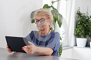 telemedicine concept, old woman with tablet pc during an online consultation with her doctor in her living room