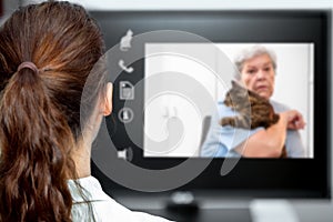 Telemedicine with the veterinarian, vet looking at the desk, elderly woman and a cat on live chat