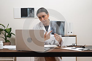 telemedicine video call, doctor presents X-ray films on laptop screen to the patient.