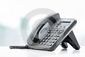 Telephone devices at white office desk with light effect, communication technology concept. VOIP or IP phone. Modern Phone VoIP.