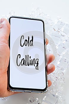 A telephone lying in the ice with the words `cold calling` Pharse, business concept of contacting and establishing cooperation