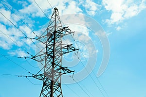 Telephone pole and wires against blue sky with clouds