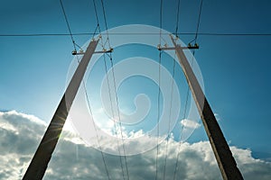 Telephone poles and wires against blue sky with clouds