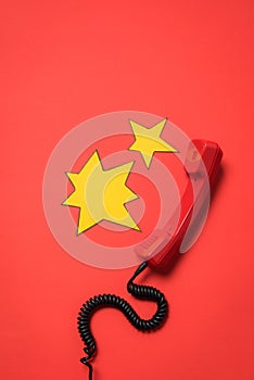 Telephone receiver and blank star shaped speech bubbles isolated on red