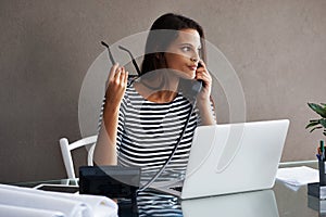 Telephone, serious and business woman in conversation, talking or listening to contact with glasses in startup office