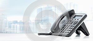 Telephone with VOIP on white table on blurred city background. customer service support, call center concept. Modern Phone VoIP.