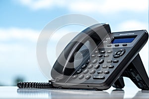 Telephone with VOIP on white table by window with blurred sky background. customer service support, call center concept. telephone