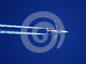 Telephote view of a red and white passenger jet flying at high altitude