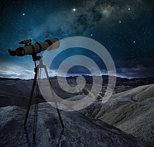 Telescope pointing the milky way in a rocky desert