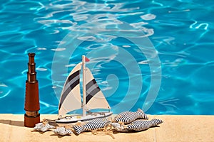 Telescope, ship and textile stuffed fish next to the pool