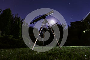 A telescope standing at backyard with night sky in the background. Astronomy and stars observing concept.