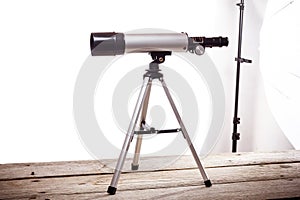 Telescope on a white background laid on wooden board