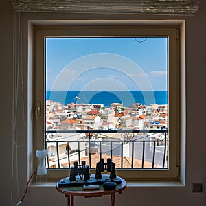 Telescopes on round table before a window view of Ionian sea and Zakynthos town in Greece
