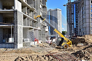 Telescopic handler work at the construction site. Construction machinery for loading. Tower crane during construct a multi-storey photo