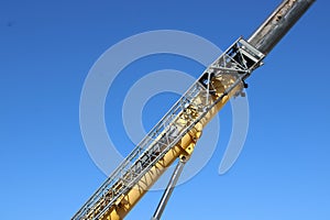 A Telescoping section of far-reaching crane is seen on a blue sky..