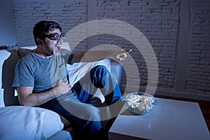 Television addict man on sofa watching TV in funny nerd geek glasses laughing crazy