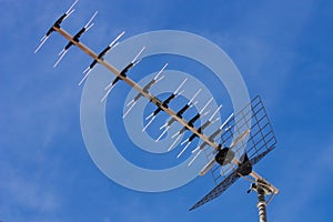 Television antenna facing left over blue sky
