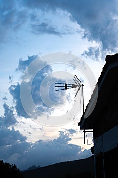 Television antenna of a house with cloudy sky in the background
