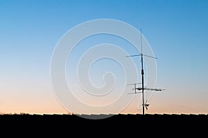 Television antenna or radio antenna on a roof in sunrise or sunset with blue sky and dusk or dawn colors show telecommunications