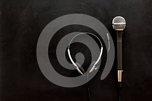 Television concept. Microphone and headset on black background top-down copy space