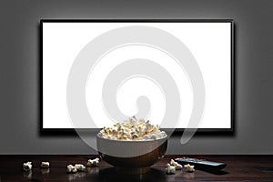 Television on a gray wall with remote control and popcorn bowl on the table. White blank HD monitor mockup.