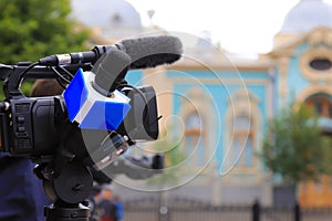 Television journalist with a microphone and a camera at a mass event, press conference. Blue microphone and equipment