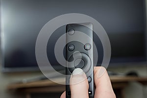 Television remote control changes channels thumb on the blue TV screen