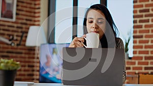 Teleworker checking emails on laptop, enjoying cup of coffee photo