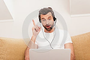 Surprised teleworker in headset pointing with photo